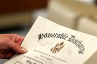 A woman holds a military discharge paper.