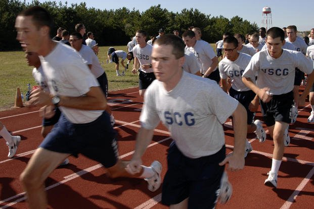 Coast Guard recruits run around a track.