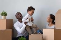 A couple plays with a child near some boxes.