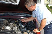 man checking under car hood