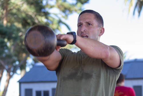 A Marine does a kettlebell swing as part of HITT training.