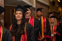 Marines dressed in graduation gowns line up to get their diplomas.