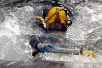 A U.S. Navy diver uses a scrubber to clean the hull of the Key West