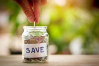 A hand drops coins into a glass jar labeled "save"
