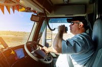 A man drives a truck and talks on the radio.