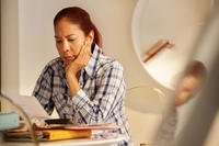 A woman looks in concern at paperwork.